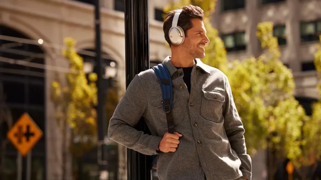 Homem usando fones JBL Tour One M2 com cancelamento de ruído em ambiente urbano ao ar livre